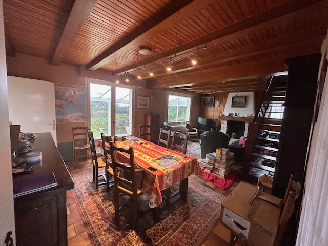 Salon rustique avec poutres foncées et cheminée ancienne avant transformation.